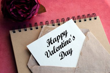 Üzerinde beyaz bir isim plakası olan eski bir zarf. Üzerinde pembe bir arkaplan ve bir çiçek var. Doğal ışık. Şenlik konsepti. Yazı, Sevgililer Günü, Anneler Günü ya da Kadınlar Günü ile ilişkilidir..