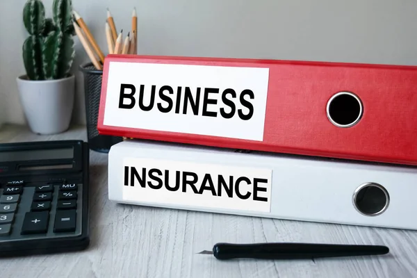 Red and white folders with documents lying on the desktop next to a calculator and a pen. The lettering on the folder has financial or marketing significance. Business concept.