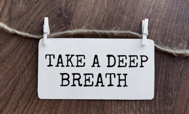 SİZE BİR DEEP BREATH MÜZİK bir kağıt parçasına sarma iğneleriyle birlikte yazılır. Yukarıdan bak. Üzerinde yazı olan rozet ahşap bir masada duruyor. Yaratıcı harfler.