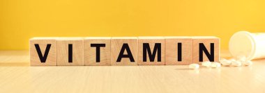 Sarı arka planda, tahta küplerin üzerine yazıtlar ve haplar.