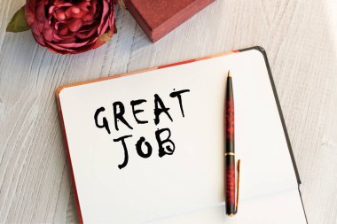 Bir çiçek ve klasik bir hediye kutusuyla birlikte bir ışık masasında yazılı defter. Doğal ışık. Yukarıdan bak. Kutlama konsepti.