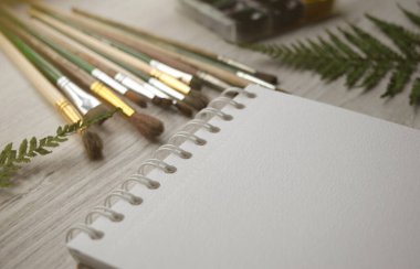 Çizim malzemeleri evdeki masaüstünde. Serbest çalışan, evde eğitim gören. Sanat malzemeleri, fırçalar, albümler, notlar masanın üstünde..