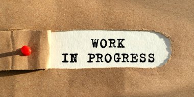 Yırtılan kağıdın arkasında Progres 'te çalışan metin görülüyor. Kraft kağıdı yırtılmış. Kağıdın kenarını kırmızı bir iğneyle çivileyeceğiz. Yukarıdan görüntüle.