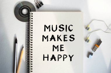 Defterdeki yazı. Müzik beni mutlu ediyor. Kahve, kulaklık ve defterleri olan sessiz bir iş yeri. Rahatlatıcı müzikle bir anlık rahatlama ve kopukluk. Yukarıdan görüntüle.