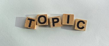 Tahta küplere yazılmış TOPIC yazıları. Arka planda, masanın üstünde. Firma ve markanın tanıtımı için grafiksel kaynaklar.