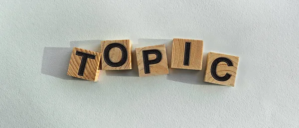 Tahta küplere yazılmış TOPIC yazıları. Arka planda, masanın üstünde. Firma ve markanın tanıtımı için grafiksel kaynaklar.