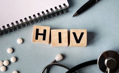 Üzerinde HIV yazan tahta küpler masanın üzerinde yatıyordu. Yukarıdan bak. Yakınlarda steteskop, defter ve dağınık haplar var..