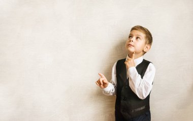 Okul üniformalı dalgın çocuk ilk kez okula gidiyor. Kapalı alanda hafif bir arka planda öğrenci. Harfleriniz için ücretsiz arkaplan hazır. Doğal duygular.