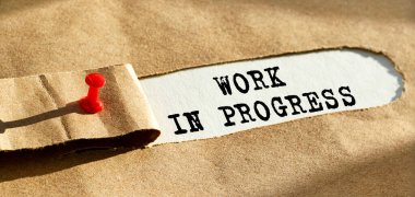 Yırtılan kağıdın arkasında Progres 'te çalışan metin görülüyor. Kraft kağıdı yırtılmış. Kağıdın kenarını kırmızı bir iğneyle çivileyeceğiz. Bir açıdan görüntüle.