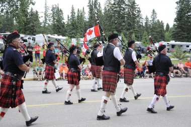 Waskesiu, Saskatchewan, Kanada - 1 Temmuz 2019: The Prince Albert Highlanders Band ve bir RCMP ve Parks Canada Color Guard Kanada bayramını kutlamak için Prince Albert Ulusal Parkı 'nda yürüyüş.