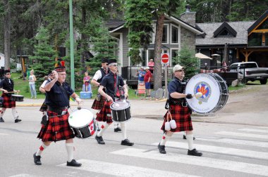 Waskesiu, Saskatchewan, Kanada - 1 Temmuz 2019: The Prince Albert Highlanders Band ve bir RCMP ve Parks Canada Color Guard Kanada bayramını kutlamak için Prince Albert Ulusal Parkı 'nda yürüyüş.