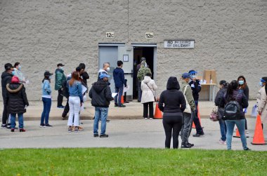 Scarborough, Ontario, Canada, May 6, 2021: People wait in line for a Covid-19 vaccine at the pop-up vaccine clinic at L'Amoreaux Collegiate, 2501 Bridletown Circle in Scarborough, Ontario, Canada. clipart