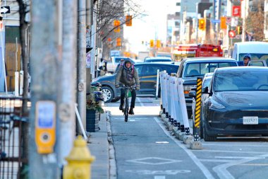 TORONONONONONTO, ONTARIO, CANADA - 12 Aralık 2024: Bisikletçiler bisikletlerini Toronto şehir merkezindeki Bloor Caddesi üzerindeki bisiklet yollarında sürüyorlar.