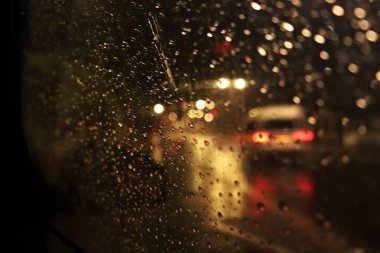 Plajın yakınındaki nemli ve soğuk bir gecede arabanın camından çekilen çekim sokak lambaları parlıyor ve geçen arabalar, arabanın camına düşen yağmur ışığı yansıtıyor. Araba geçiyor, penceredeki su damlalarına odaklanıyor..