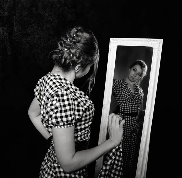 Vrouw in een shirt in de spiegel kijken — Stockfoto