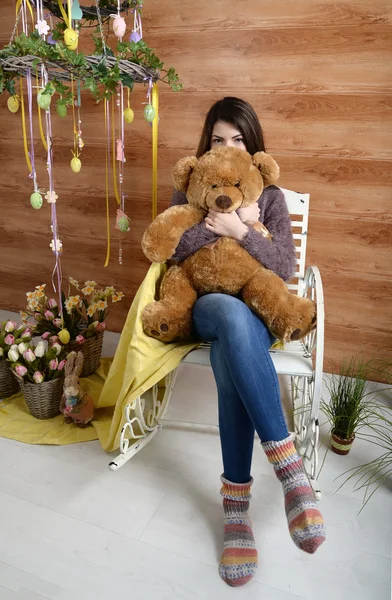 Angry girl with a plush bear sitting on a chair — Stock Photo, Image