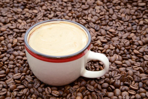 Cup of coffee with cream on a coffee beans background — Stock Photo, Image