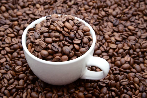 Taza con granos de café sobre un fondo de granos de café — Foto de Stock