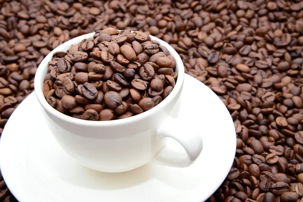 Taza con granos de café en un platillo — Foto de Stock