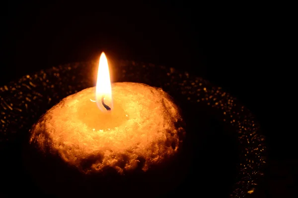 White candle on a plate burning on a black background — Stock Photo, Image