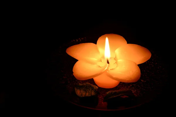 Vela en forma de flor ardiendo sobre un fondo negro — Foto de Stock