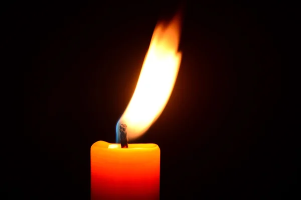 Orange candle burning on a black background — Stock Photo, Image