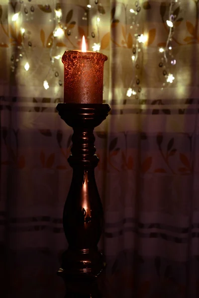 Orange candle over christmas lights — Stock Photo, Image