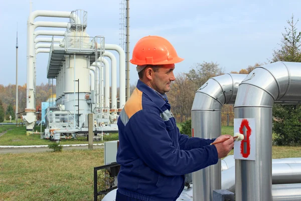 Worker draws arrows on pipes — Stock Photo, Image