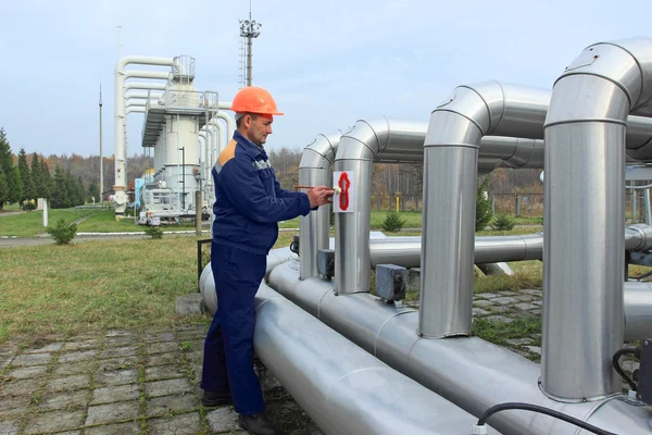 Worker draws arrows on pipes — Stock Photo, Image