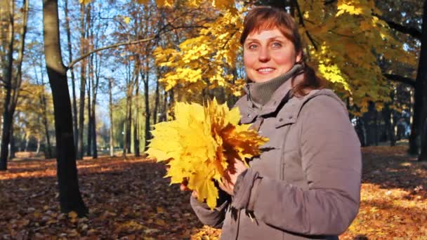 Женщина стоит с листьями — стоковое видео