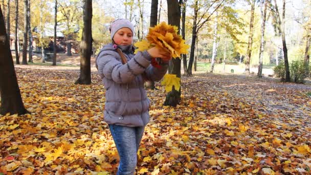 Meisje staat en verstrooit bladeren — Stockvideo