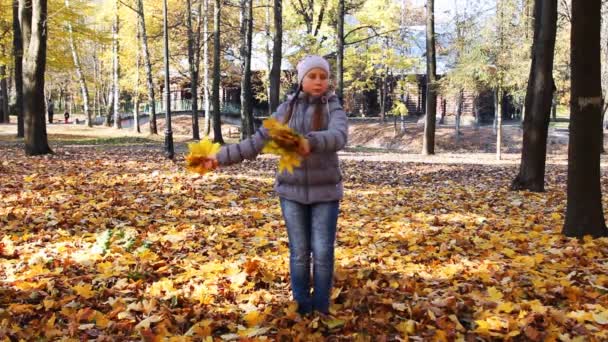 Chica gira y dispersa hojas — Vídeos de Stock