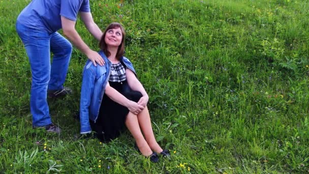 Женщина и мужчина сидят на траве — стоковое видео