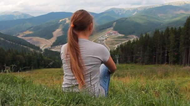Flickan sitter tillbaka på grönt gräs — Stockvideo
