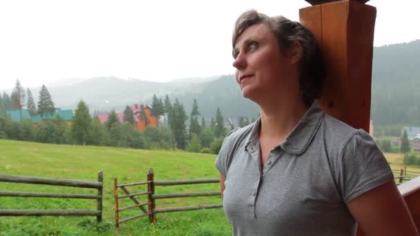 Женщина стоит на крыльце рядом с домом — стоковое видео