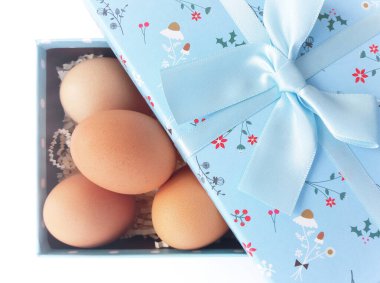 Beyaz arka planda hediye kutusunda paskalya yumurtaları.