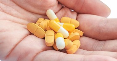 Sarı haplar ve kapsüller ellerinde. Sağlık kavramı.