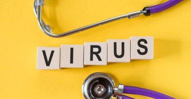 VIRUS, sarı masada steteskoplu tahta küplü binalar olduğunu söylüyor. Salgın, ağrı kesici, grip ve koronavirüs konsepti..