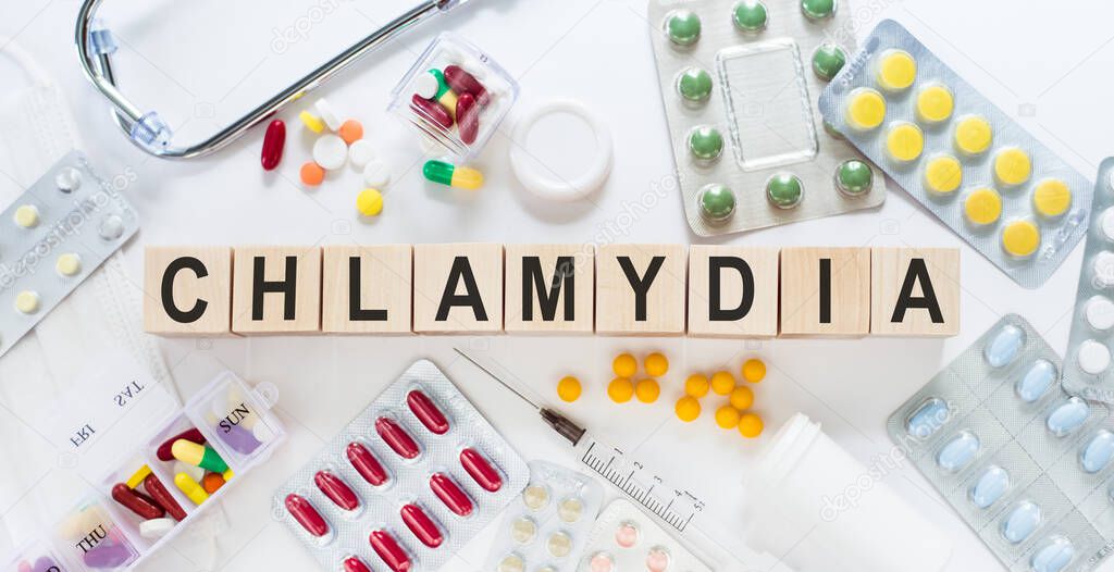 Chlamydia - word from wooden blocks with letters, parasitic bacterium chlamydia concept with pills, vitamins, stethoscope and syringe on the background