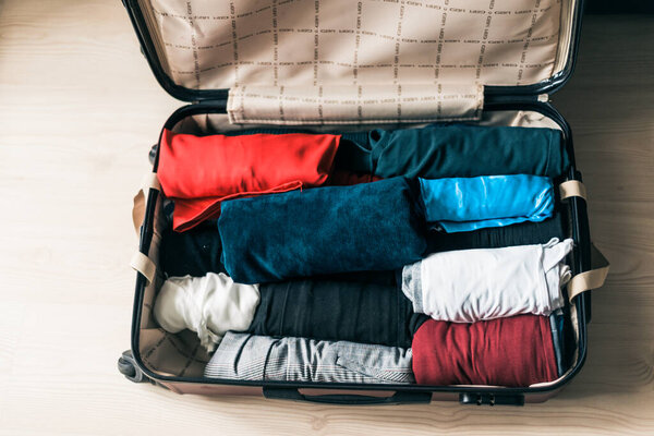 Packing luggage for a new journey. Suitcase with things on the wooden floor