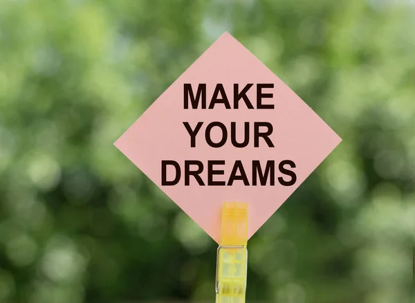 Make your dreams, text a piece of paper on notes on a green background. Concept desire to keep the selected goals and dreams.