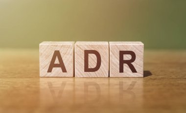 ADR (abbreviation for Adverse Drug Reaction) word written on wooden blocks on a wooden table. Medical concept. clipart