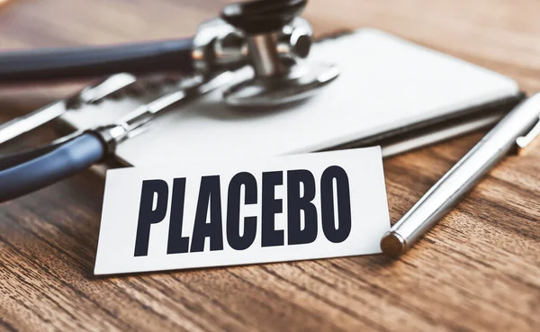 在有医疗背景的木制桌子上卡片上写的Placebo字 — 图库照片