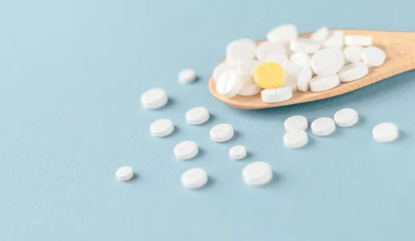 Weiße Tabletten Und Eine Gelbe Auf Einem Holzlöffel Auf Blauem — Stockfoto