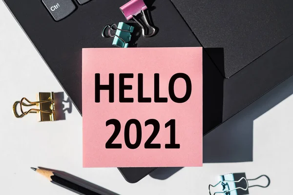 HELLO 2021 note is written on a paper sticker on a laptop keyboard.