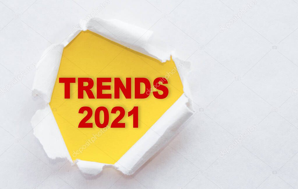 Top view of white torn paper and TRENDS 2021 text on yellow background.