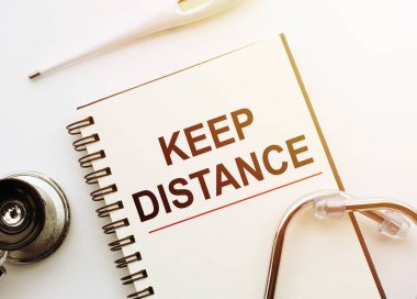 Tıbbi konsept. Üzerinde kelime KEP uzaklığı olan defter stetoskop ve termometreyle beyaz masada. Coronavirüs.