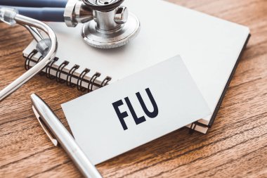 FLU, bir kalem ve steteskopun yanındaki ahşap masadaki bir deftere yazılmıştır. Tıbbi konsept.
