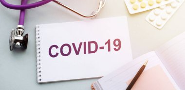 Stetoskop ve tabletlerle tıbbi geçmişinde COVID-19 yazılıydı.