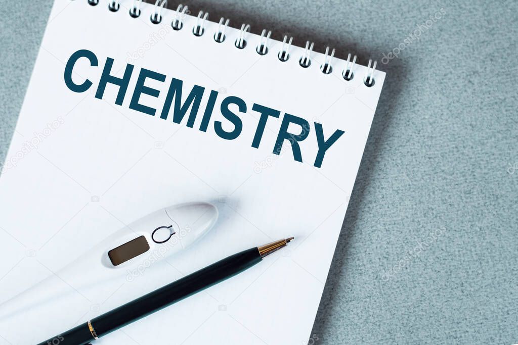 Blank notebook with thermometer and pen on table CHEMISTRY text.